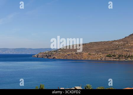 Eine ruhige Küstenlandschaft mit ruhigem blauem Wasser, einer felsigen Küste und einem klaren Himmel Stockfoto