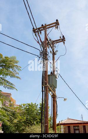 Hölzerne Versorgungsmasten mit elektrischen Drähten gegen blauen Himmel. Stockfoto