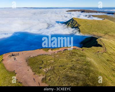 Wanderer auf einem Berggipfel mit Blick auf eine atemberaubende Wolkenumkehr in Wales Stockfoto
