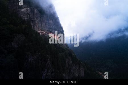 Das Kloster Sumela schmiegt sich an eine Klippe im türkischen Macahel Valley, umgeben von stimmungsvollem Nebel und dunklem Wald. Stockfoto