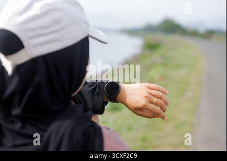 Muslimische Frau Überprüft Smartwatch Während Des Outdoor Workouts Stockfoto