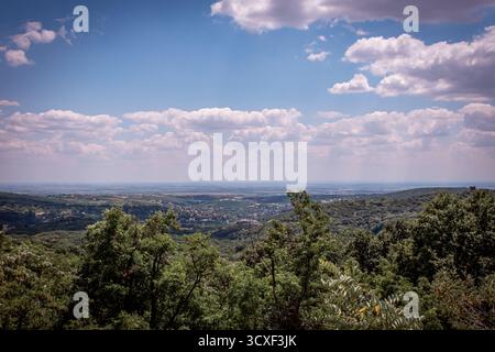 Fruska Gora in Serbien ist ein grünes Tal mit Wäldern, in der Ferne ist ein Dorf zu sehen. Stockfoto