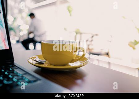 Moderner Laptop mit leerem schwarzen Bildschirm auf Holztisch neben Kaffeetasse und Smartphone Stockfoto
