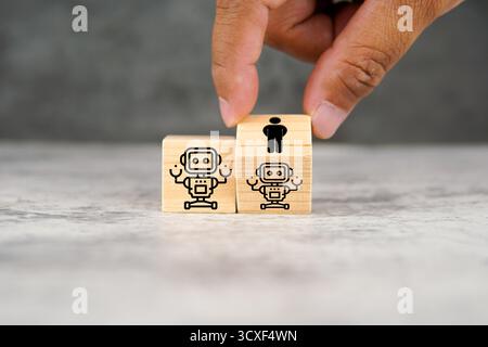 Menschliche Hand platziert Holzwürfel mit Roboter und menschlichen Ikonen nebeneinander und symbolisiert künstliche Intelligenz, menschliche Zusammenarbeit, Automatisierung. Stockfoto