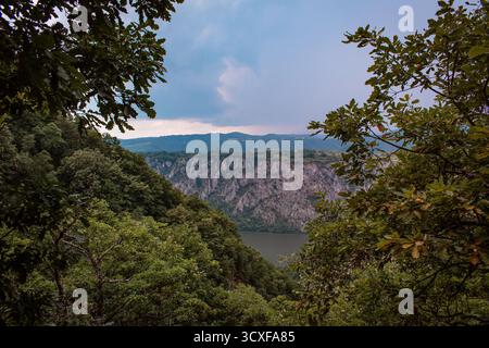 Die Donau fließt entlang der Grenze zwischen Serbien und Rumänien. Eine atemberaubende Landschaft mit Bergen und felsigen Klippen, bedeckt mit Wäldern und Moos. Stockfoto