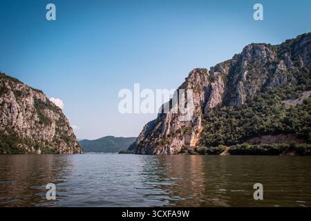 Die Donau fließt entlang der Grenze zwischen Serbien und Rumänien. Eine atemberaubende Landschaft mit Bergen und felsigen Klippen, bedeckt mit Wäldern und Moos. Stockfoto