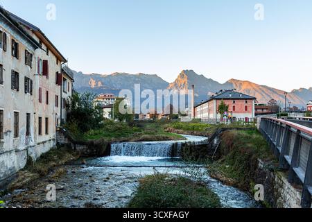 Malerischer Blick auf Feltre in der Provinz Belluno, Veneto, Italien, von einem ruhigen Fluss, der durch ein bezauberndes Dorf fließt, umgeben von majestätischen Stockfoto