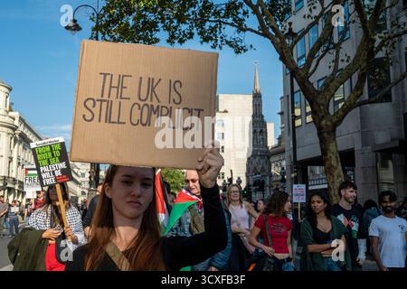 Nationale Demonstration für Palästina, London. Junge Frau mit dem Schild "das Vereinigte Königreich ist immer noch Mitschuld". Stockfoto