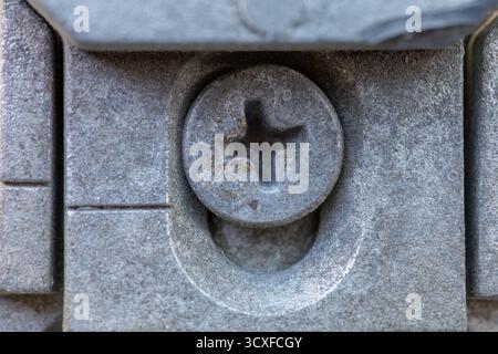 Nahaufnahme eines schmutzigen, rostigen Schraubenkopfes auf grauer Metalloberfläche, Industriekonzept Stockfoto