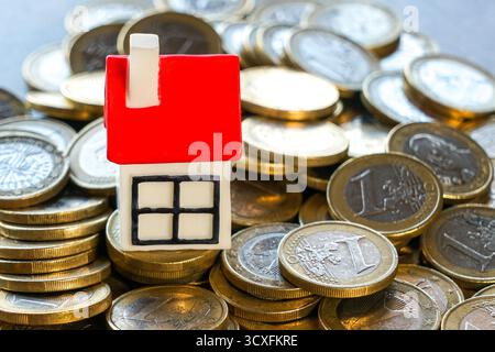 Miniaturhaus mit rotem Dach auf Stapeln von Euro-Münzen. Konzept für Immobilien, Hypotheken, Wohnungsmarkt, Spareinlagen, Investitionen, und Property FIN Stockfoto