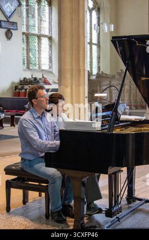 Emma Abbate und Julian Perkins treten in der St Michael's Church Framlingham ein Nachmittagskonzert mit Klavierduetten auf einem Flügel auf Stockfoto