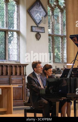 Emma Abbate und Julian Perkins treten in der St Michael's Church Framlingham ein Nachmittagskonzert mit Klavierduetten auf einem Flügel auf Stockfoto