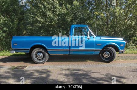 Nijkerk, Gelderland, Niederlande - 09.07.2025: Klassischer blauer GMC-Pickup-Truck parkt auf sonniger Straße mit Bäumen im Hintergrund, Vintage-Automobil-Stil Stockfoto
