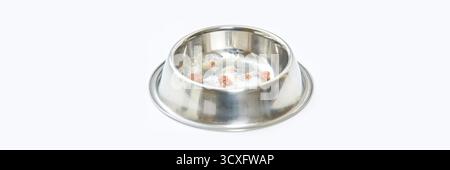 Leere Tierschale aus Edelstahl mit Lebensmittelrückständen auf weißem Hintergrund. Stockfoto