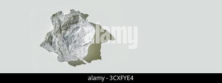 Zerknitterte Aluminiumfolienkugel, die Schatten auf hellgrauer Oberfläche wirft. Stockfoto
