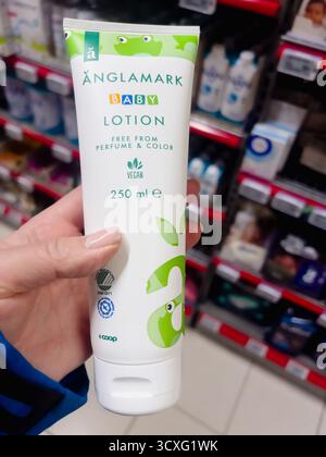 Dalen, Norwegen - 11. Oktober 2025: Anglamark Babylotion in der Hand mit grünem Design und veganem Etikett, mit Körperpflege im Verkaufsregal platziert Stockfoto