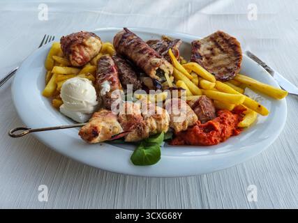 Ein gemischter Grill mit Pommes frites, Burger, Wurst, Schweinefleisch und Kebab Stockfoto