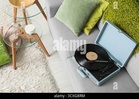 Inneneinrichtung des stilvollen Wohnzimmers mit Couchtischen und Plattenspieler auf grauem Sofa Stockfoto