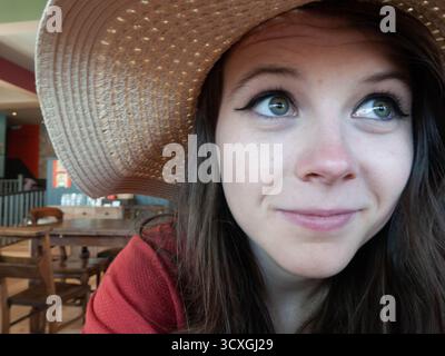 Eine junge Frau mit Strohhut lächelt im Café-Restaurant Stockfoto