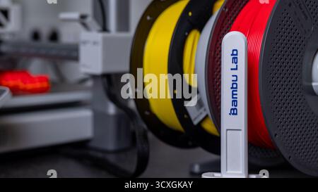 Jurmala, Lettland - 14.10.2025: Nahaufnahme Filament für 3D-Drucker Bambu Lab A1 mit AMS. Farbenfrohe 3D-Druckfilamente auf Spulen in einem modernen Arbeitsbereich Stockfoto
