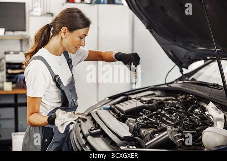 Ein erfahrener Mechaniker arbeitet fleißig an einem Automotor in einer belebten Autowerkstatt Stockfoto