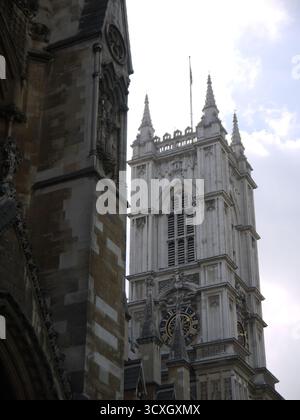 Gotische Kathedralfassade mit verzierten Türmen und Uhrenturm vor bewölktem Himmel Stockfoto