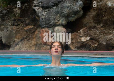 Frau, die sich in einem Pool mit geschlossenen Augen entspannt und die ruhige Atmosphäre genießt. Radium Hot Springs, BC Stockfoto