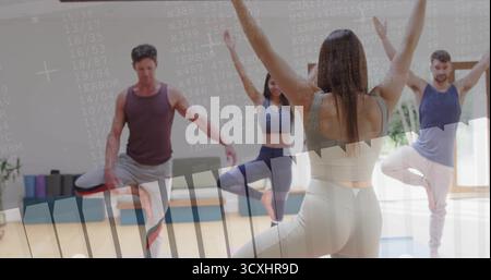 Leitender Instruktor in beigefarbener Activewear, der Yoga-Kurs in Baumhaltung im Studio mit Yogamatten führt Stockfoto