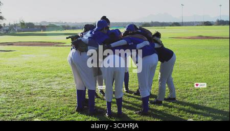 Acht Baseballspielerinnen, die sich auf dem Spielfeld mit Teamtrikots und Handschuhen unterhalten Stockfoto