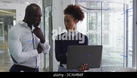 Zuhören reifer Geschäftsmann in Anzug, während ein Kollege Daten auf Laptop in der Lobby des Büros vorstellt Stockfoto