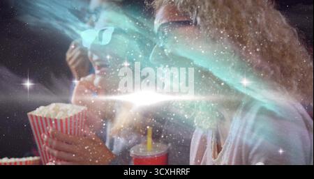 Popcorn in der Hand, rote Tasse, zwei Frauen mit 3D-Brille, die im Theater unter kosmischem Licht Filme sehen Stockfoto