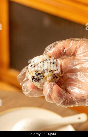 Hand in Handschuh mit hausgemachtem Reisball Stockfoto