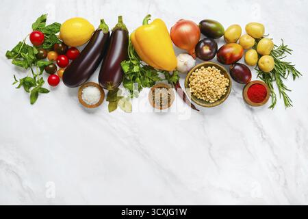 Eine bunte Auswahl an frischem Gemüse und Kräutern umfasst Tomaten, Auberginen, Gurken, Paprika, Kartoffeln, und verschiedene Gewürze, die auf einem Ligh angeordnet sind Stockfoto