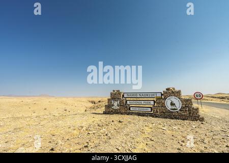 Steineingangsschild zum Namib-Naukluft-Nationalpark in Namibia, 27. August 2025: Umgeben von Wüstenebenen und weit entfernten Bergketten Stockfoto
