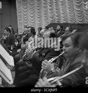 Ein Nahaufnahme-Archivfoto aus dem Jahr 1984 zeigt die Bläser- und Bläserabschnitte des Orchesters im Kulturpalast von Sloviansk. Männliche Musiker zeigen intensive Konzentration, während sie während einer Aufführung Horn und Saxophon spielen. Das Bild zeigt die Fähigkeiten und Hingabe, die für das pulsierende kulturelle Leben in der ukrainischen SSR von zentraler Bedeutung sind. Dies ist ein kraftvolles Dokument der Gemeinschaftskunst und des kreativen Geistes eines friedlichen Donbas vor dem Krieg. Stockfoto