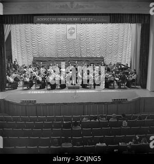 Ein Archivfoto aus dem Jahr 1984 zeigt ein Sinfonieorchester auf der Bühne des Artem Palastes der Kultur in Sloviansk, Ukrainische SSR. Ein Dirigent führt die Musiker vor einem Publikum, das im Saal sitzt. Über der Bühne zeigt ein prominentes Banner den klassischen leninistischen Slogan: „Kunst gehört dem Volk“. Die Szene fängt das reiche kulturelle Leben einer typischen sowjetischen Industriestadt ein. Dieses Bild ist ein wertvolles Dokument der Kunst und Ereignisse der Gemeinschaft in einem friedlichen Donbass vor dem Krieg Stockfoto