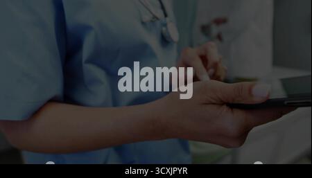 Verwendung eines Stifts Arzt mit blauen Peelings und Interaktion mit Tablette im Klinikraum, mit Stethoskop Stockfoto