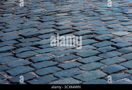 Eine Nahaufnahme einer kopfsteingepflasterten Straße mit einer blau gekachelten Oberfläche. Die Pflastersteine sind in einem Muster angeordnet, und die blaue Farbe der Fliesen steht im Kontrast zu wi Stockfoto