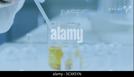 Mit Handschuhen dosieren der gelben Lösung mit Pipette in den Becher am Labortisch, mit Fläschchen und Kolben Stockfoto