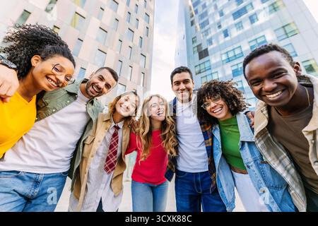 Junge Gruppe von verschiedenen Freunden umarmt und lacht draußen an der Kamera Stockfoto