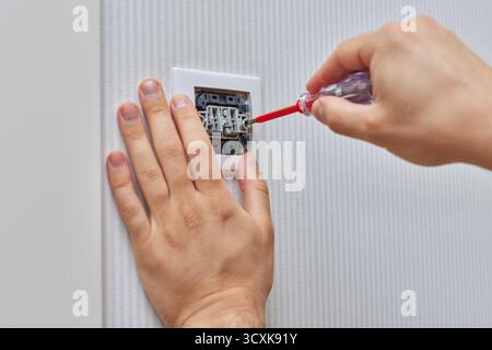 Elektriker repariert Hauslichtschalter mit Schraubendreher zu Hause, Nahaufnahme Stockfoto