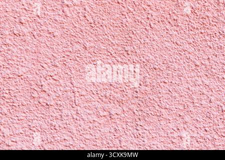 Pinkfarbene, raue Gipsstruktur mit kleinen Details und natürlicher Beleuchtung, perfekt für Hintergrunddesign und dekorative Oberflächen Stockfoto