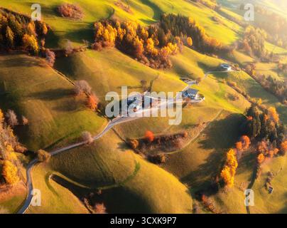 Blick aus der Vogelperspektive auf das grüne Alpental bei Sonnenuntergang mit verstreuten Dörfern, Feldern, Wäldern und sanften Hügeln in den Dolomiten, Italien. Landschaftlich reizvolle Berge lan Stockfoto