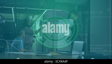 Zeigende Frau in Geschäftskleidung, die Karten an der Glaswand im Konferenzraum präsentiert, mit Laptop Stockfoto