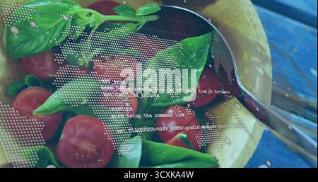 Holzsalatschale mit halbierten Kirschtomaten, Basilikum, Löffel auf blauem Tisch, digitale Überlagerung Stockfoto
