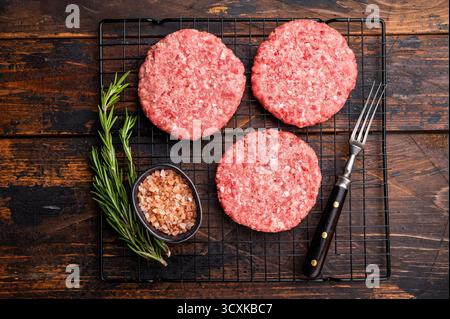 Rohe Fleischpasteten, Schnitzel, Hackfleisch für Burger. Hölzerner Hintergrund. Draufsicht. Stockfoto