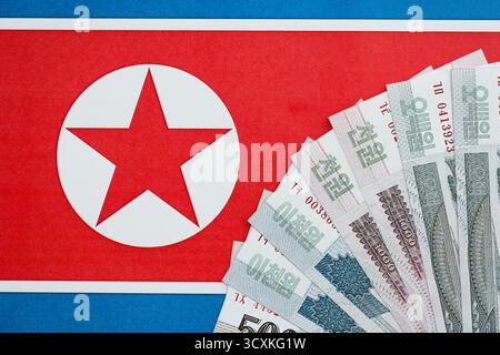 Nordkoreaner gewannen Geldscheine in großer Höhe lügen auf der Flagge der Volksrepublik Korea aus nächster Nähe. Finanz- und Bankkonzept Stockfoto
