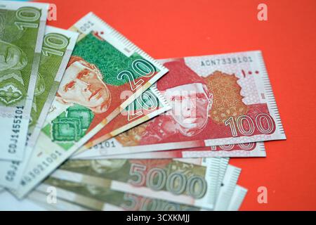 Pakistanische Rupien Banknoten auf rotem Hintergrund. Die aktuellen pakistanischen Geldrechnungen liegen in großer Höhe auf dem Tisch. Das Konzept des Geschäfts und der Investitionen in Pakistan Stockfoto