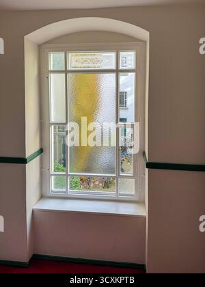 Bogenförmiges Fenster mit Milchglas und Blick auf den Innenhof Stockfoto