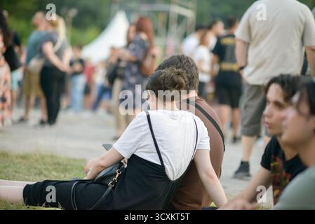 Sofia, Bulgarien — 25. Juni 2025. Während eines Rockkonzerts sitzen die Menschen auf dem Gras, ruhen sich aus und genießen die entspannte Atmosphäre unter anderen Festgästen Stockfoto